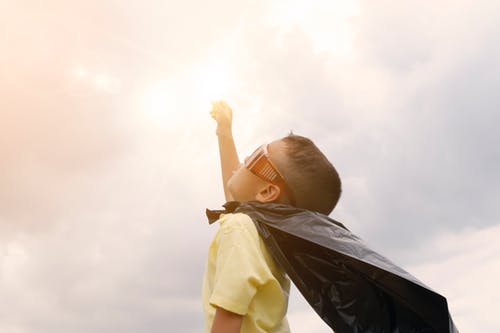 Kid with a cape looking at the sky